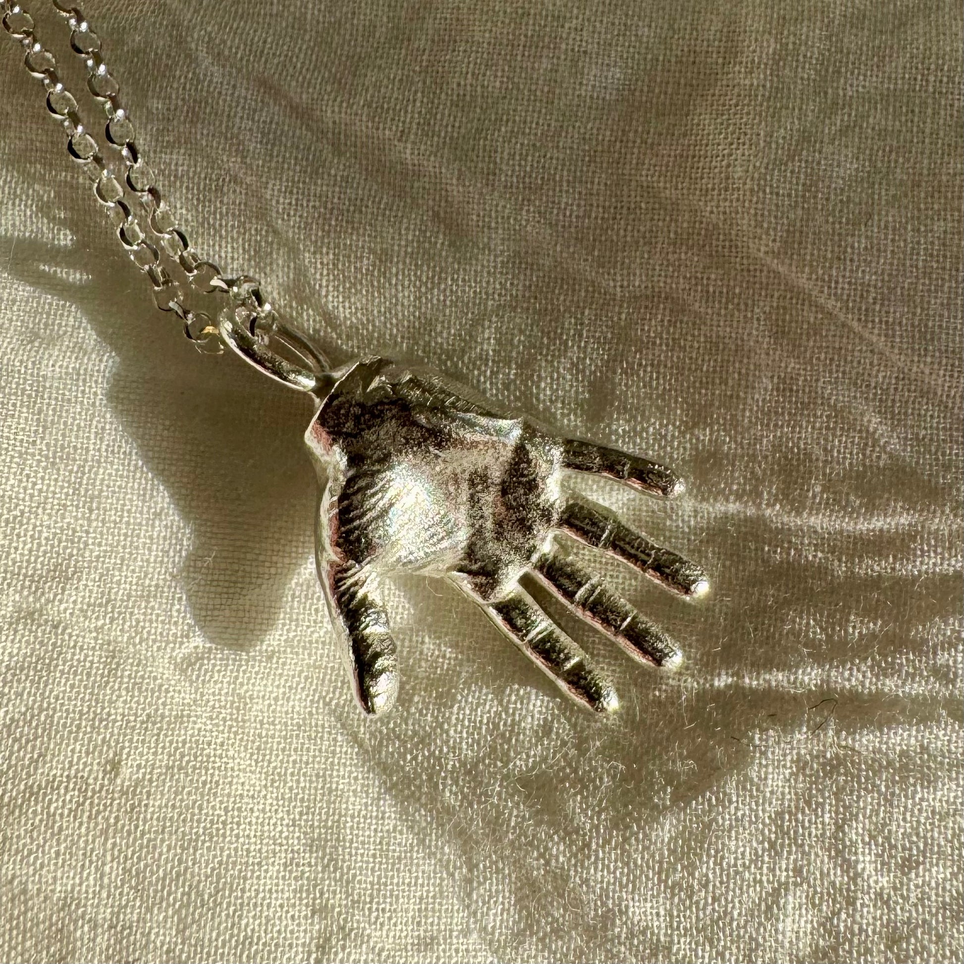 A little Hand charm cast in recycled silver and measuring 2cm by 1.5cm hanging on a 45cm recycled silver chain.