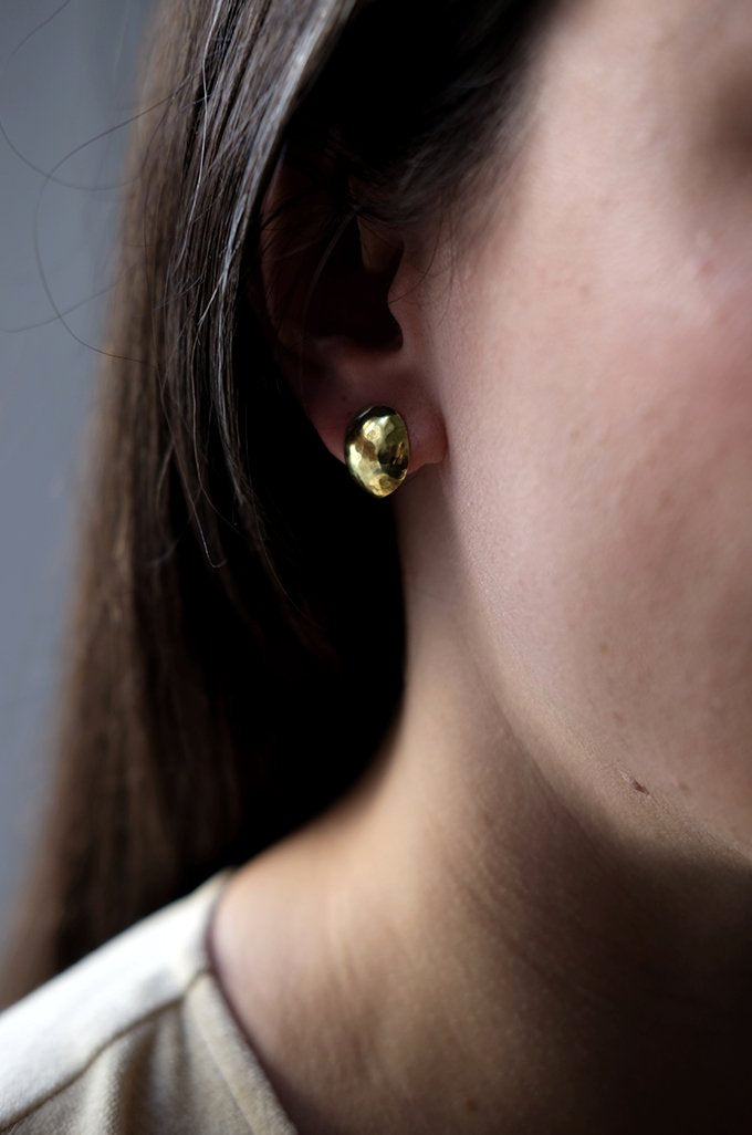 Artichoke Studs: handmade domed artichoke leaves in recycled brass, worn by a model.