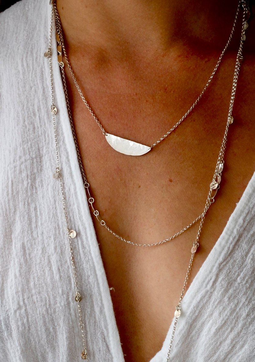 Ida Necklace: an eye catching but simple necklace with a recycled, hammered silver segment shape on a recycled silver belcher chain. Worn by a model.