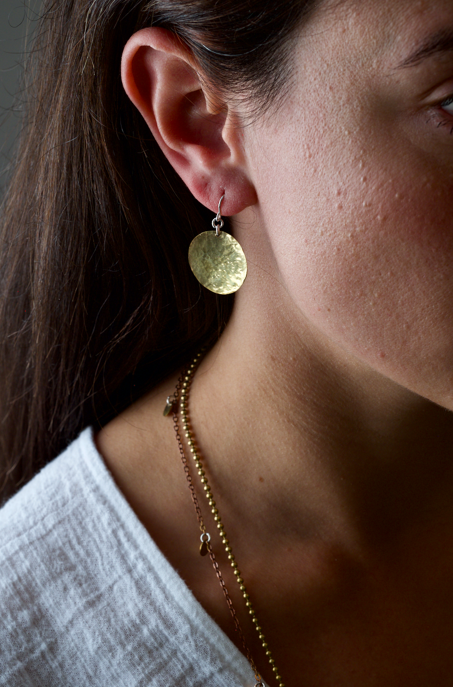 Brass Moons: Handmade recycled brass full moon disc earrings. Worn by a model.