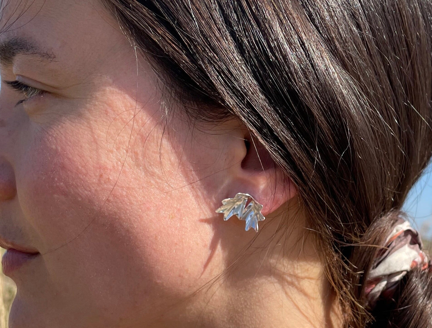 Sea Kale Studs: handmade recycled silver earrings in the folded shape of a sea kale leaf. Worn by a model.