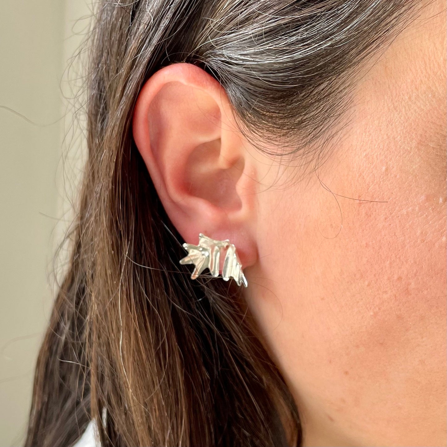 Sea Kale Studs: handmade recycled silver earrings in the folded shape of a sea kale leaf. Worn by a model.