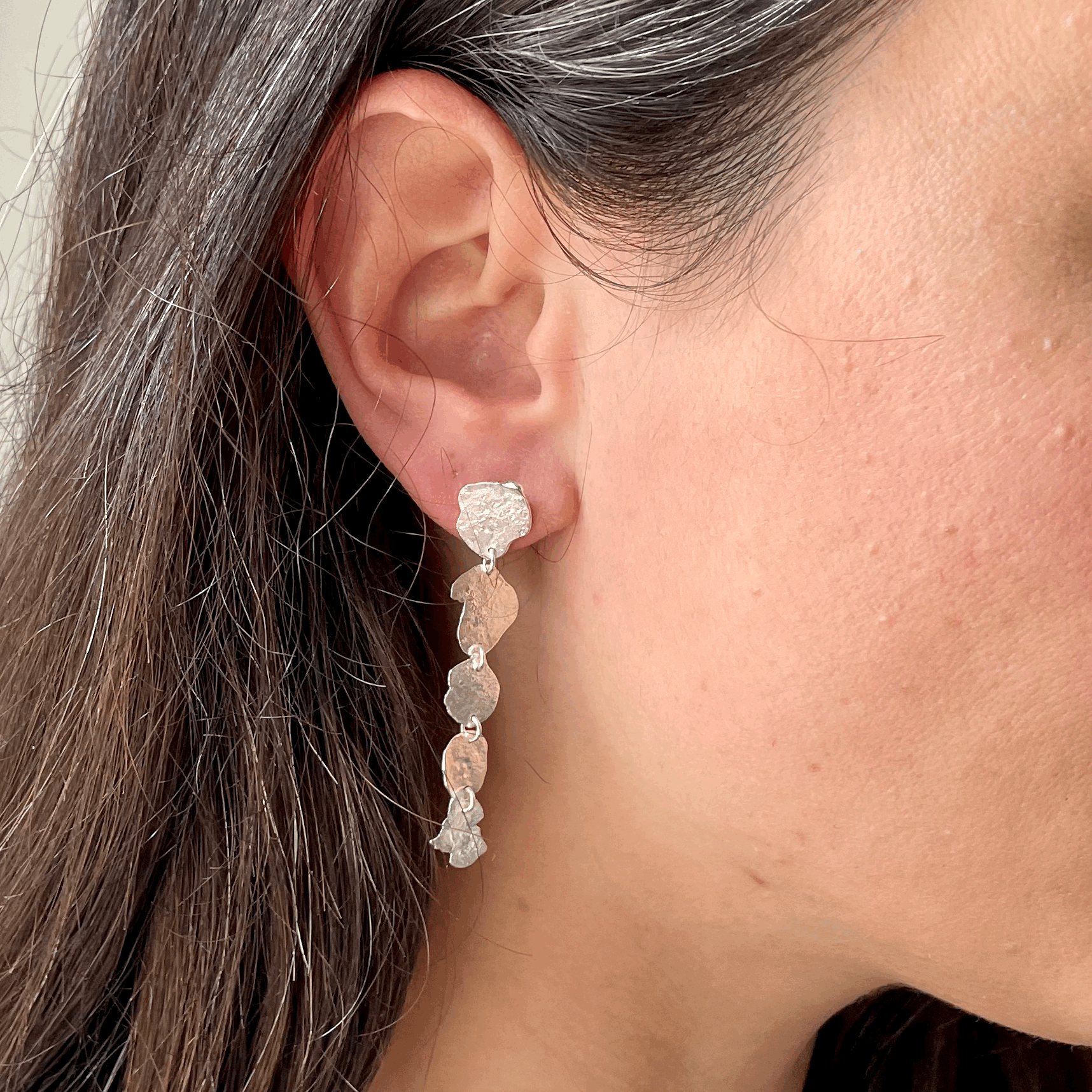 Ponds Earrings: handmade from melting recycled silver into five articulated pond shapes that move as you do. Worn by a model.
