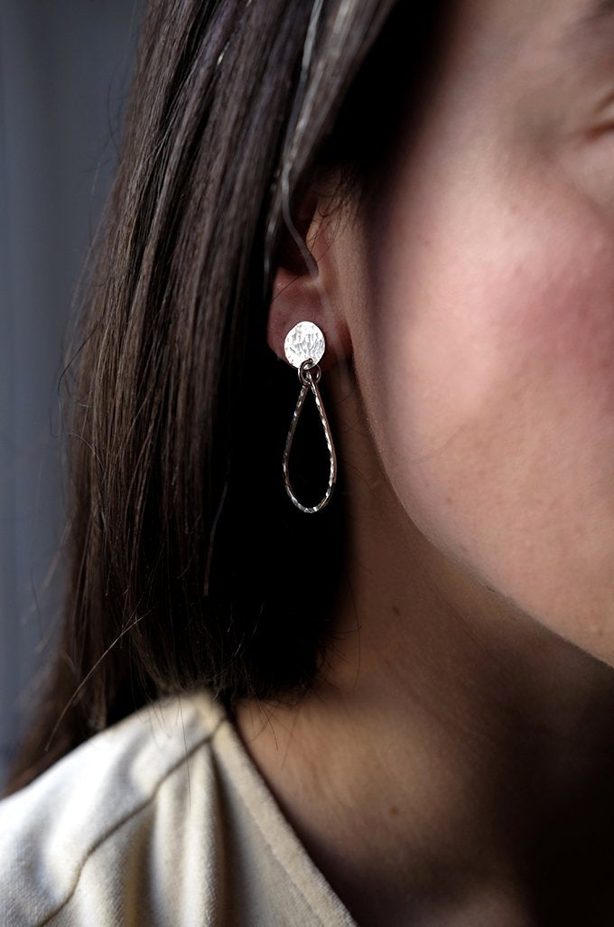 Asti Earrings: handmade recycled silver teardrop hanging from a disc, worn by a model.