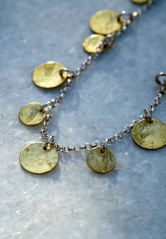Orla Necklace: a handmade necklace featuring tiny discs of hammered recycled brass hanging from a recycled silver chain.