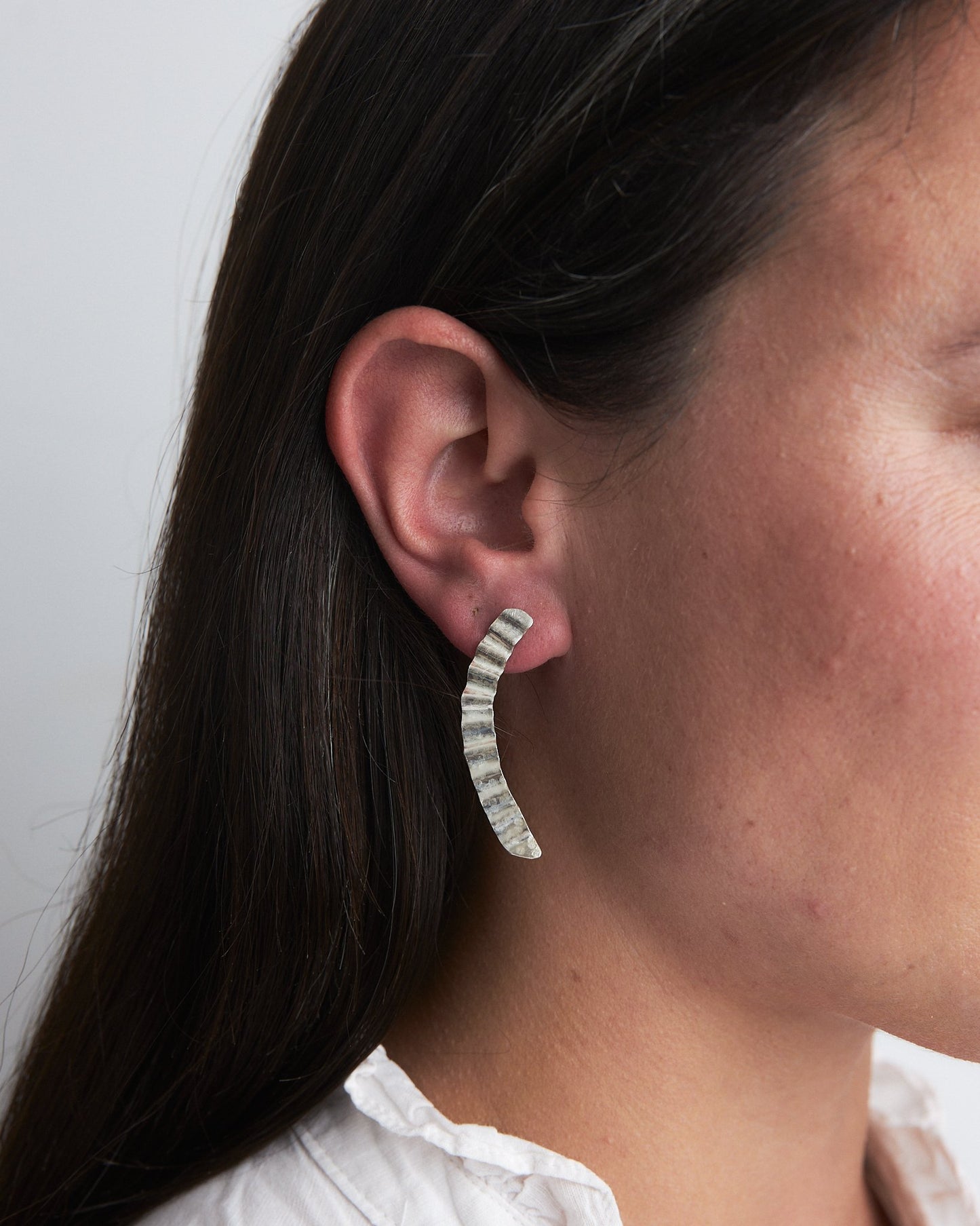 Handmade recycled silver earrings reminiscent of the rippling surface of a breeze across water, these studs have both rippling forms and curving shapes.