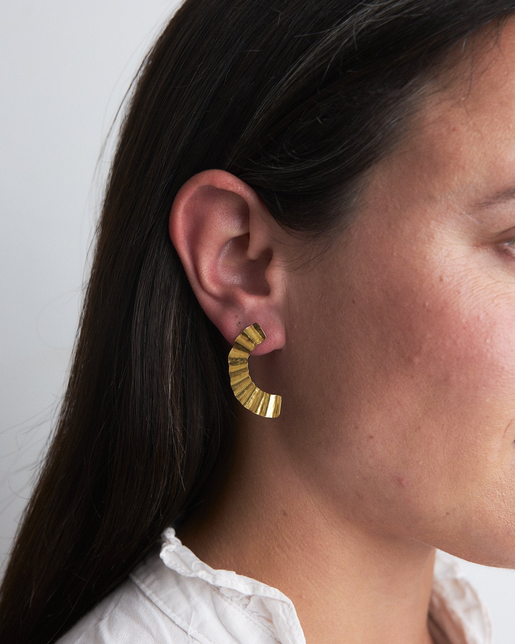 Handmade recycled brass earrings reminiscent of the rippling surface of a breeze across water, these studs have both rippling forms and curving shapes.