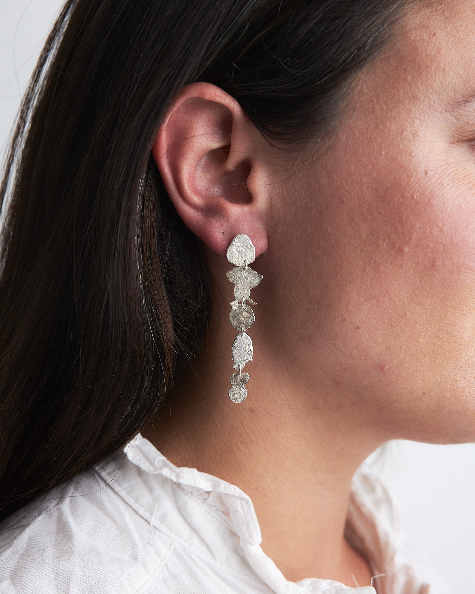 Ponds Earrings: handmade from melting recycled silver into five articulated pond shapes that move as you do. Worn by a model.