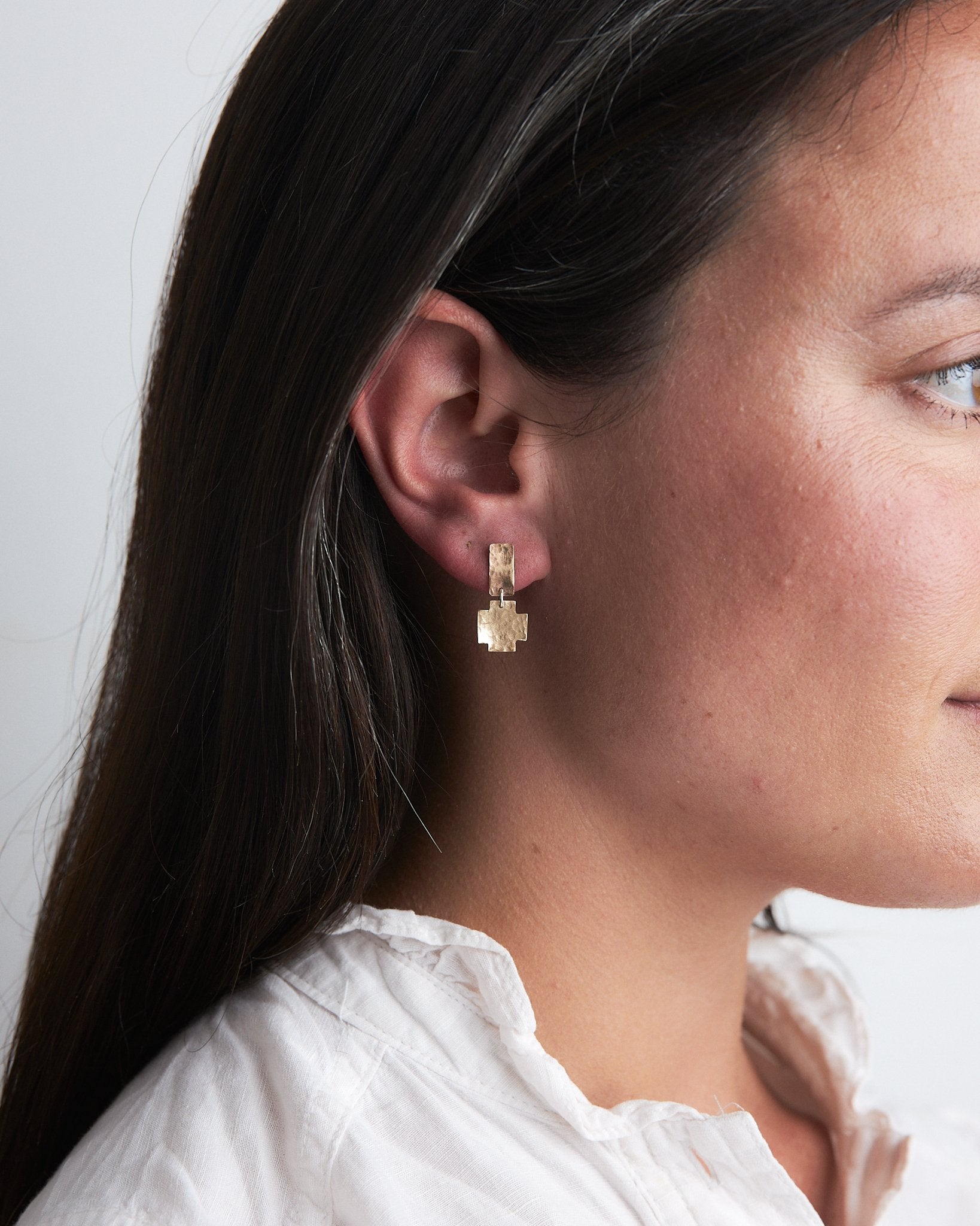 Nell Earrings: gorgeous handmade recycled gold earrings of rectangular and cross shapes. Articulated for movement and to benefit from that inimitable flash of gold. Worn by a model.