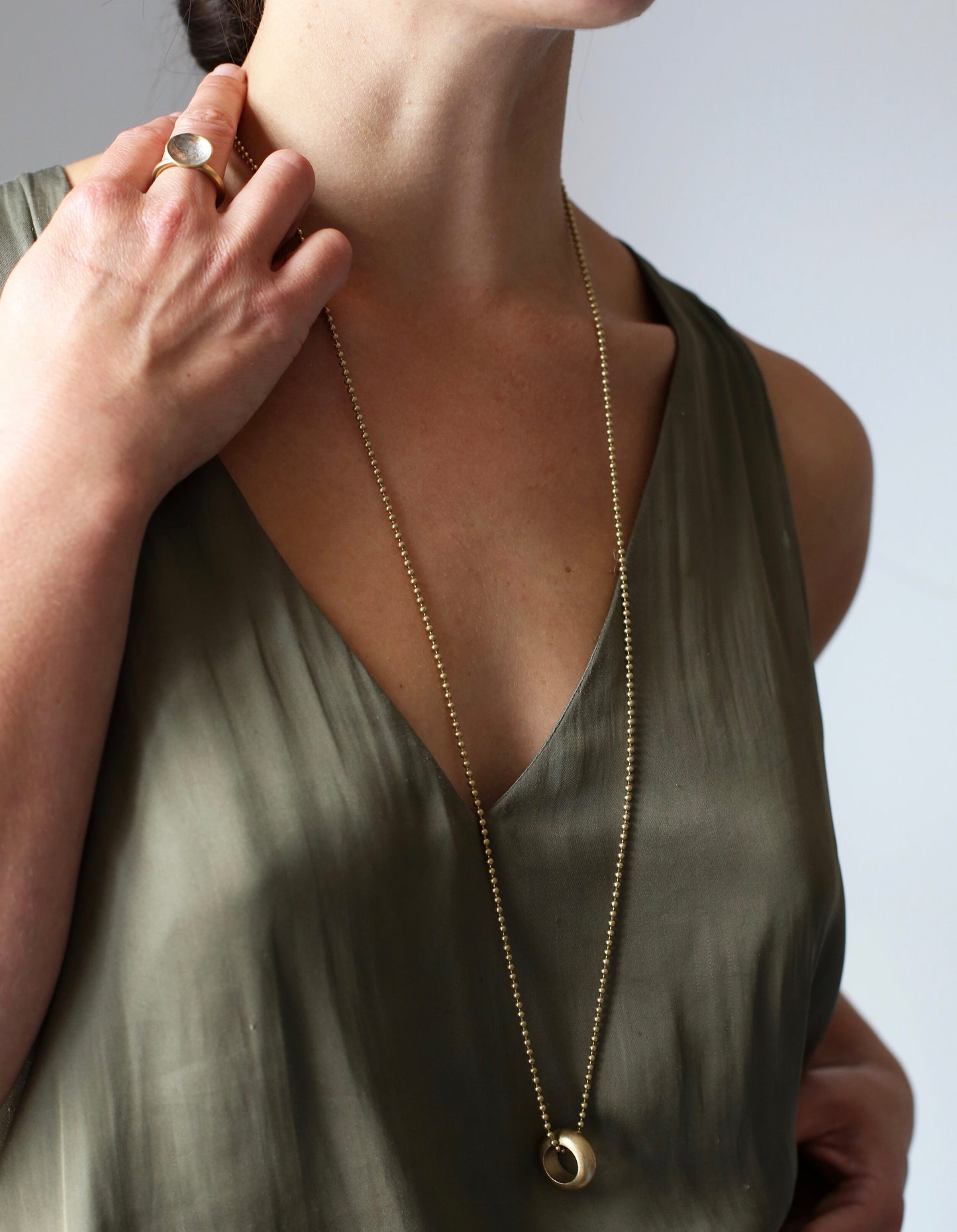 Delilah Pendant: a gorgeous handmade pendant with a tactile weighty solid brass ring on a vintage brass ball chain - strikingly simple. Worn by a model.