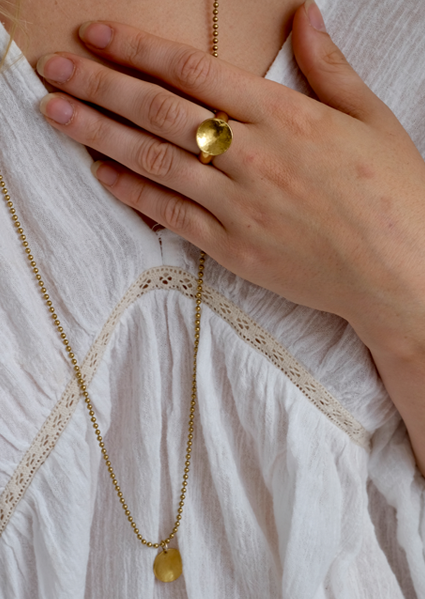 Brass Sun Ring: a lovely hunky ring handmade from recycled brass with a slightly concave domed and hammered disc on a solid recycled brass ring shank. Inspired by the sun! Worn by a model.