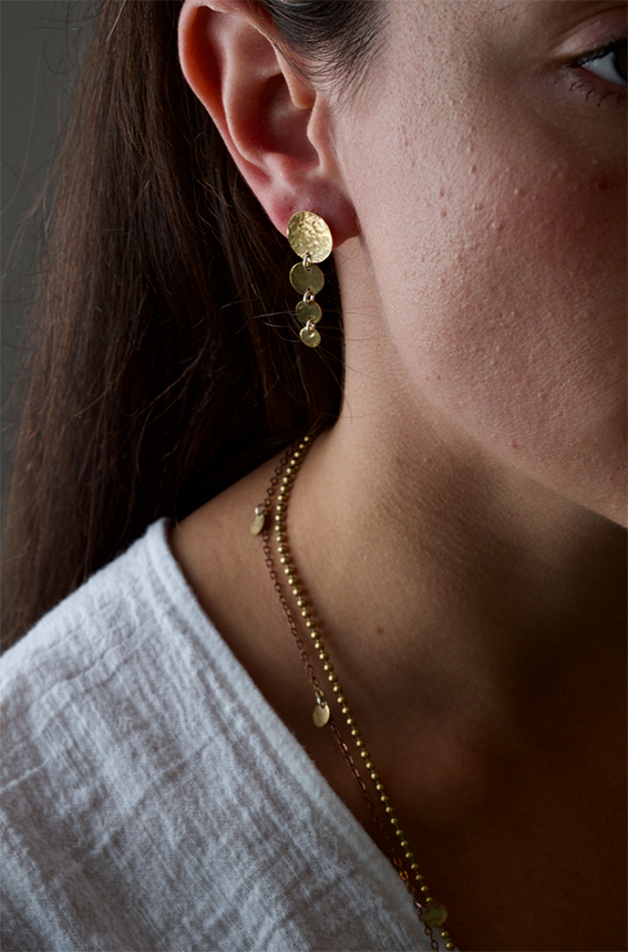 Emma Earrings: handmade earrings featuring graduated hammered recycled brass discs. Worn by a model.