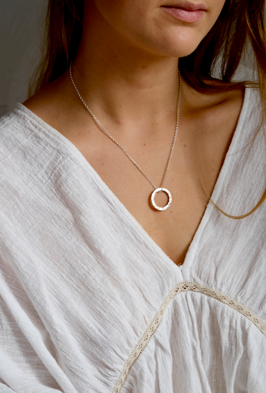 Gali Necklace: a simple and beautiful necklace with a hammered recycled silver circle on a recycled silver belcher chain. Worn by a model.