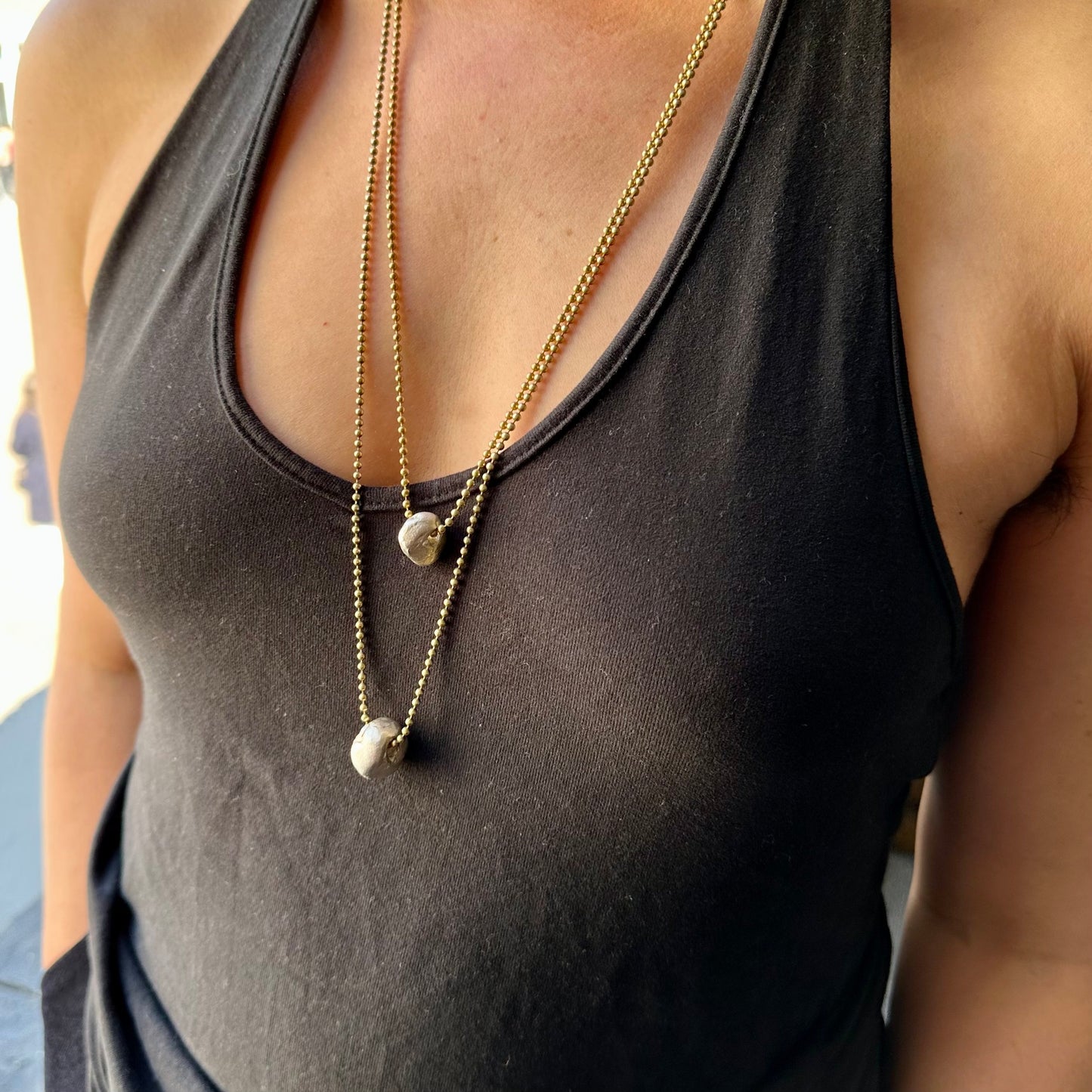 Solid silver hag stone pendants in two sizes, on brass chains, worn by a model.