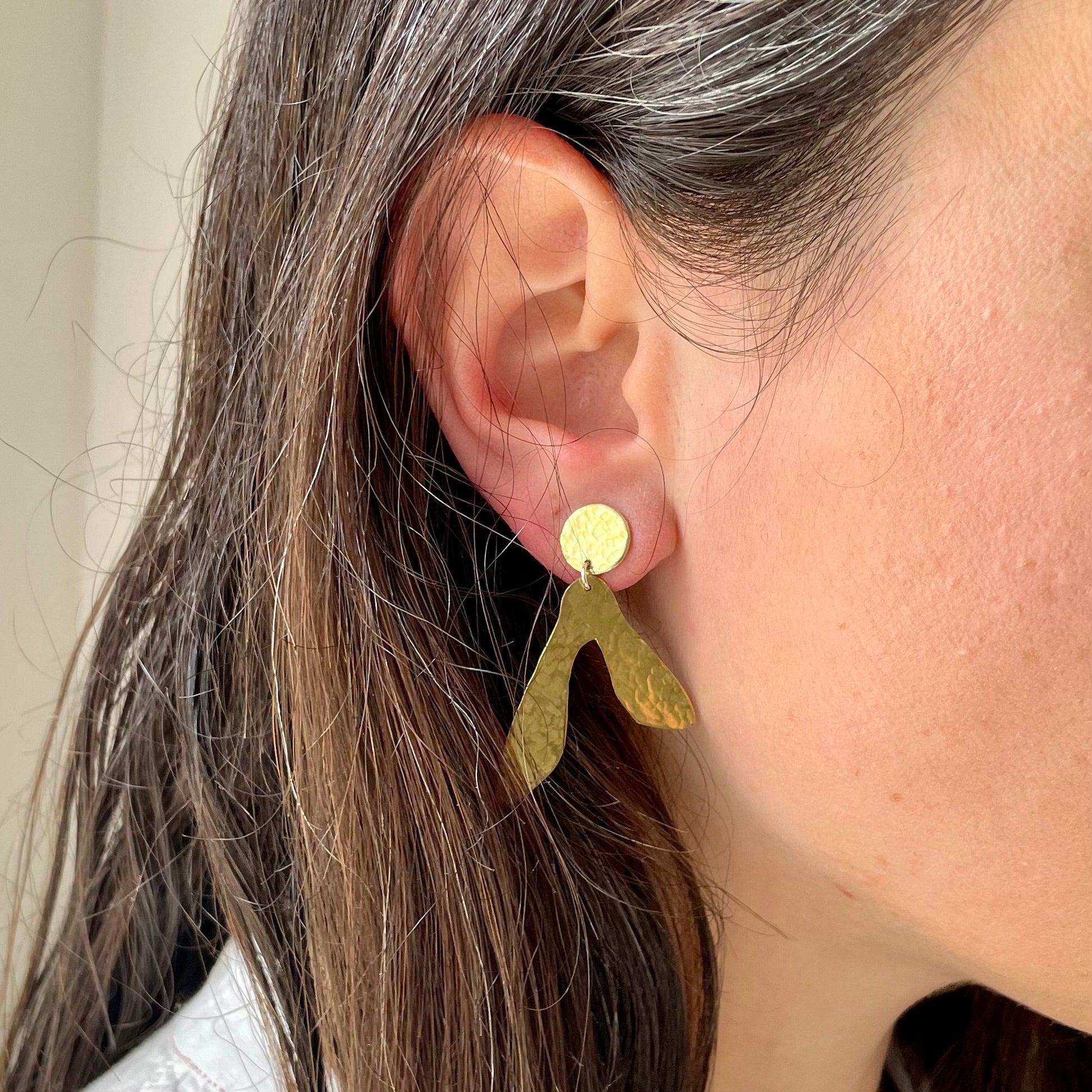 Sycamore Earrings: sycamore seed shaped earrings handmade in recycled brass, worn by a model.