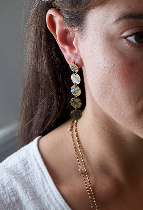 Nada Earrings: uniquely patterned brass disc earrings with swirls of molten recycled silver. Worn by a model.